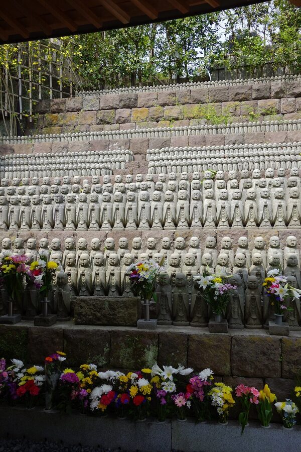 A single Jizo statue at Hase-dera in Kamakura, wearing a red knitted cap