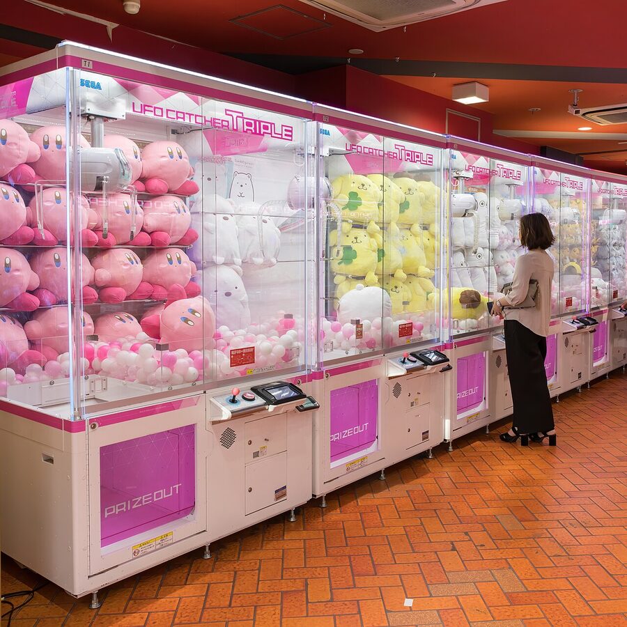 Claw cranes with kawaii stuffed mascots and woman playing in Akihabara
