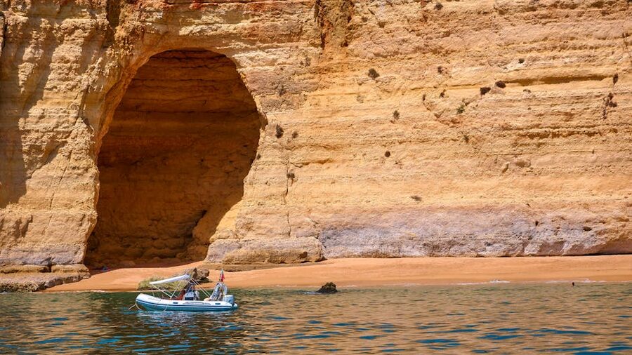 Boat cruising near eroded cliffs of the Algarve coast, Portugal