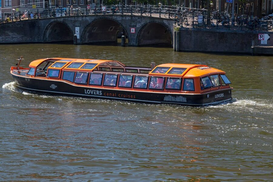 Amsterdam canal tour boat under historic stone bridge