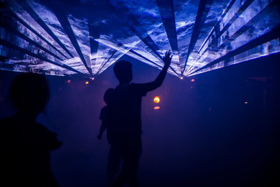Silhouettes of visitors against light display at Fabrique des Lumières