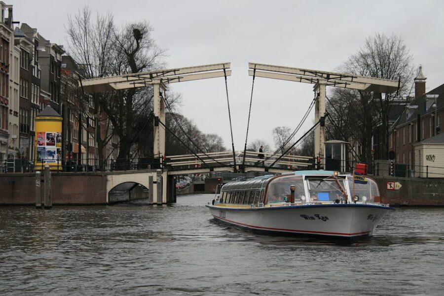 Tour boat on Amsterdam canal passing under a city bridge