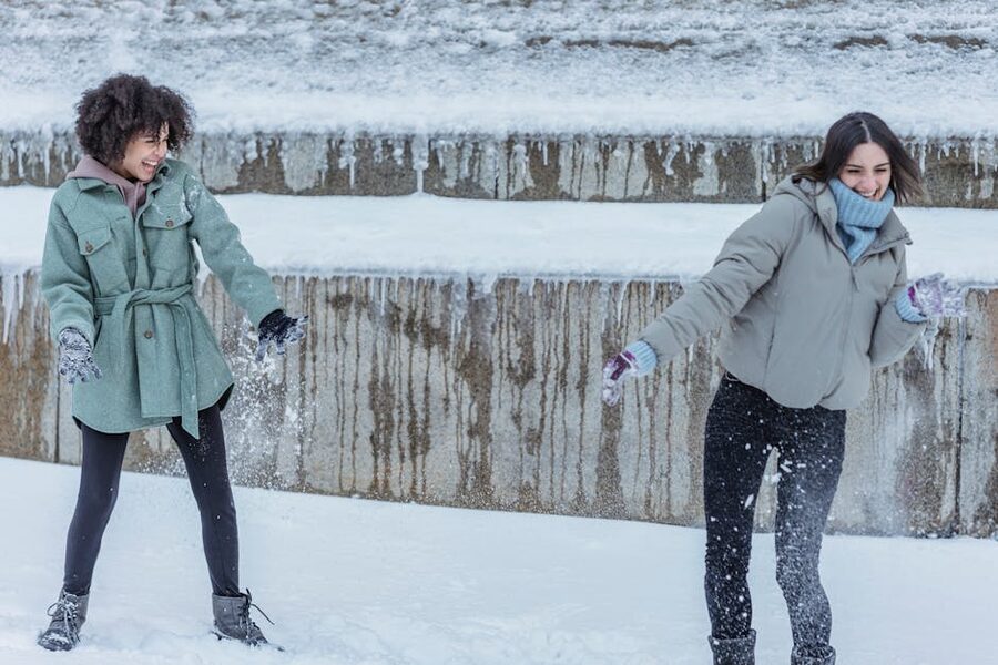 Friends laughing in winter coats outside an Amsterdam attraction