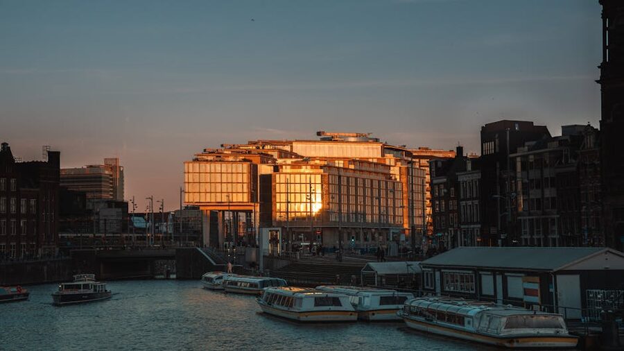 Amsterdam canal at sunset with modern architecture reflected