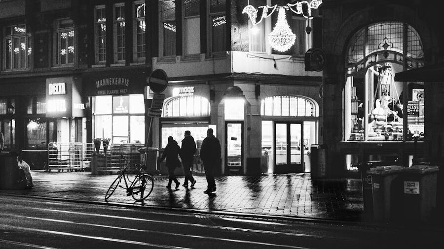 Pedestrians walking on Amsterdam cobblestones along old buildings