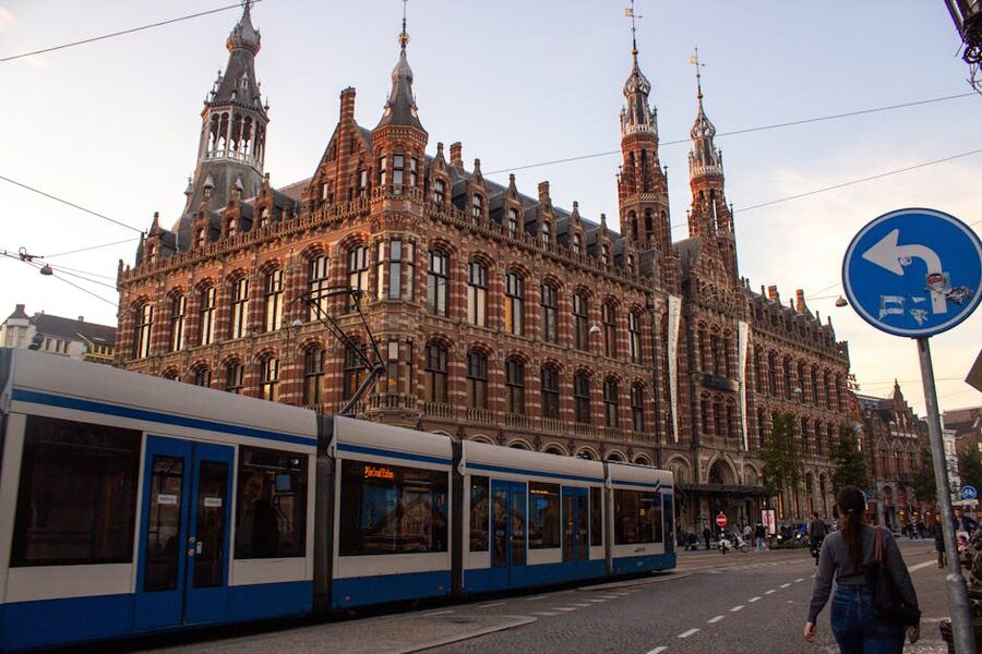 Amsterdam tram passing historic building at sunset