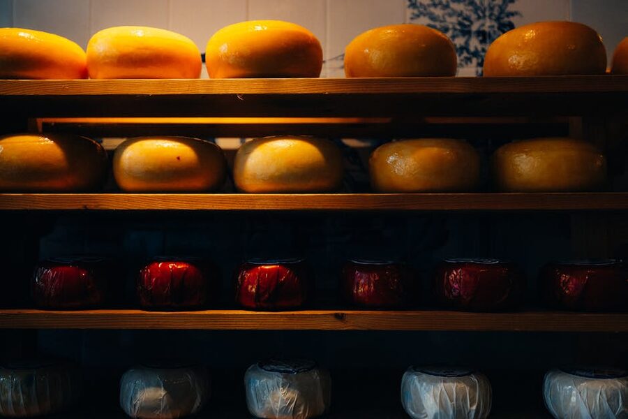 Stacks of Gouda and Edam cheese wheels on shelves