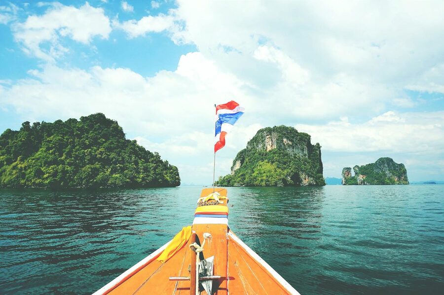 A longtail boat heading toward tropical islands in the Andaman Sea on a sunny day
