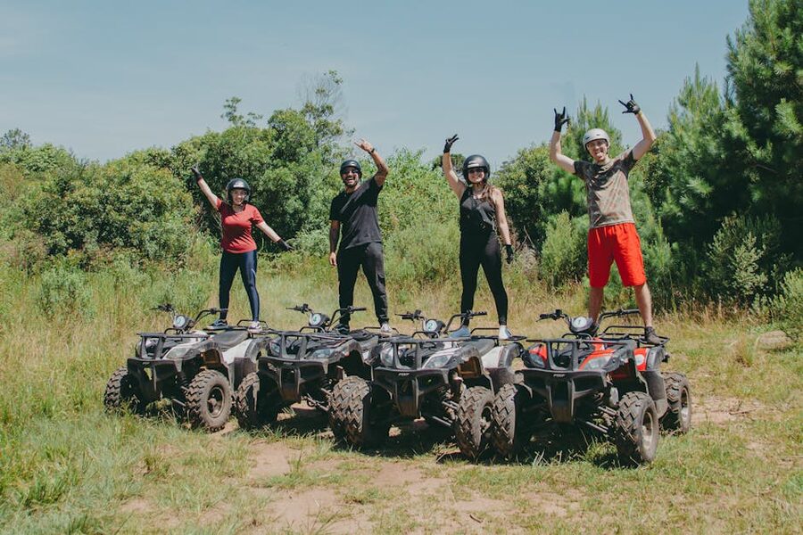Four people on an ATV group ride through a muddy forest trail