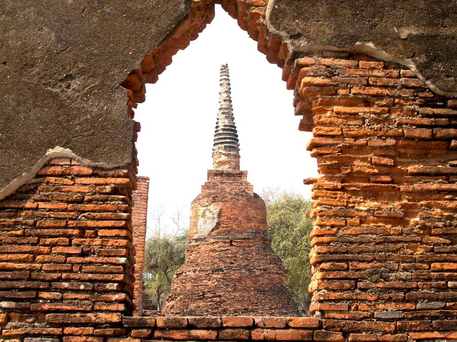 View of a temple spire framed through an ancient brick archway at Ayutthaya Historical Park