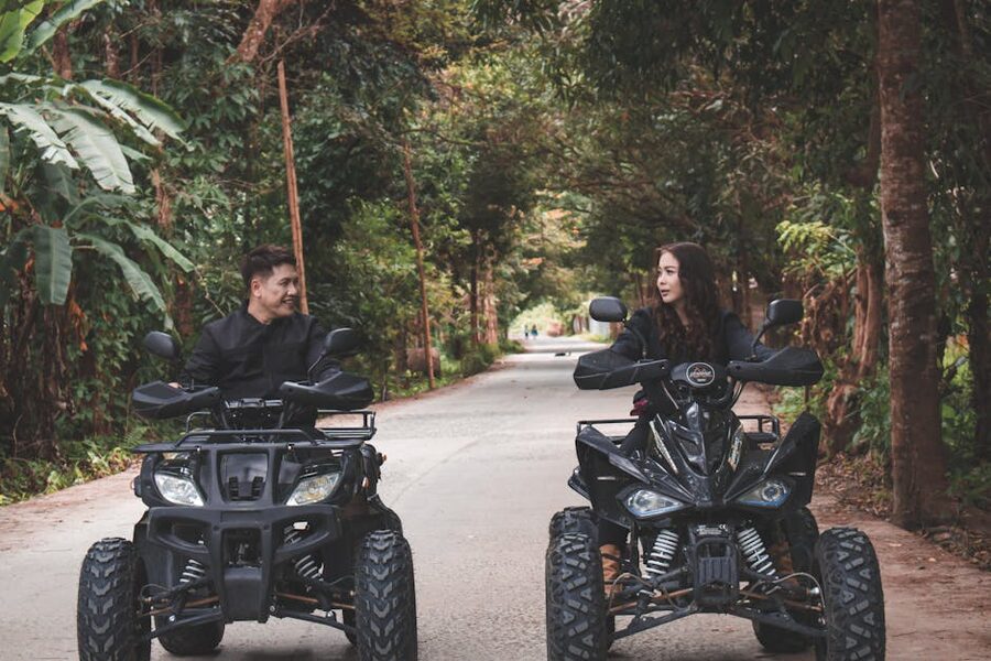 Couple on quad bikes riding through lively green rainforest