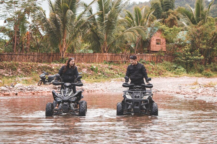 Quad bikes crossing a river through lush rainforest on an ATV tour