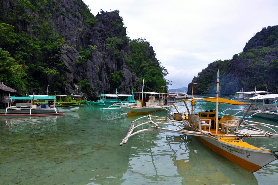 Colorful traditional banca outrigger boats on clear water in El Nido