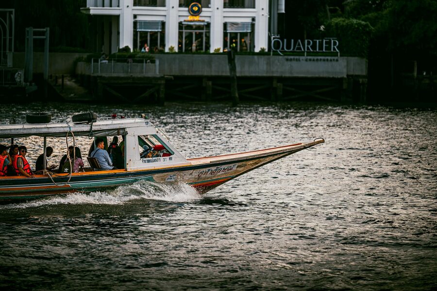 Longtail boat cruising the wide Chao Phraya River in Bangkok