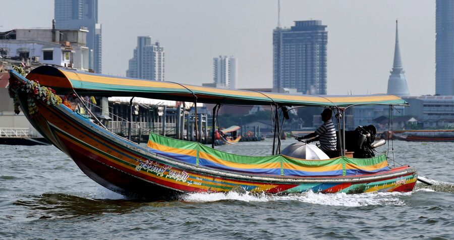 Colorful longtail boat on the Chao Phraya River with Bangkok skyscrapers in the background