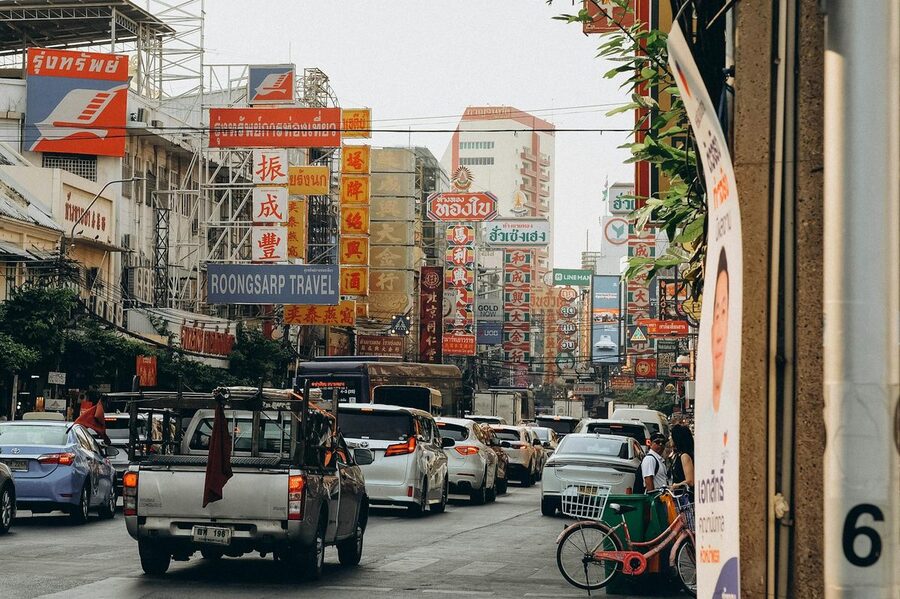 Street view of Bangkok Chinatown district with colorful signs and traffic