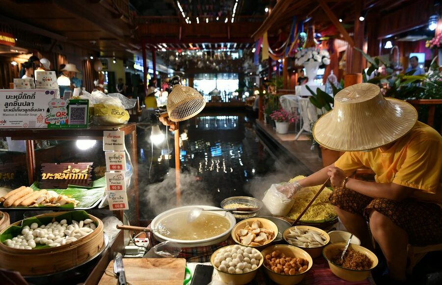 Thai street vendor preparing noodles at indoor market stall in Bangkok