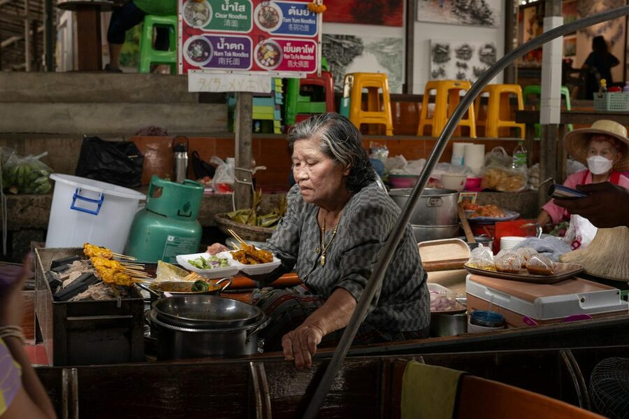 Thai street food vendor cooking traditional dishes at Bangkok market