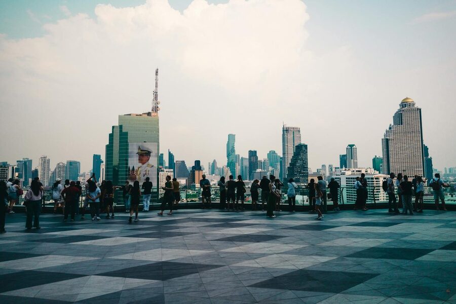 Tourists enjoying Bangkok skyline from a rooftop viewpoint