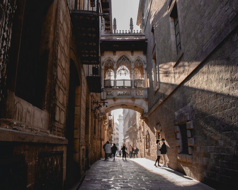 People walking under Pont del Bisbe in Barcelona's Gothic Quarter