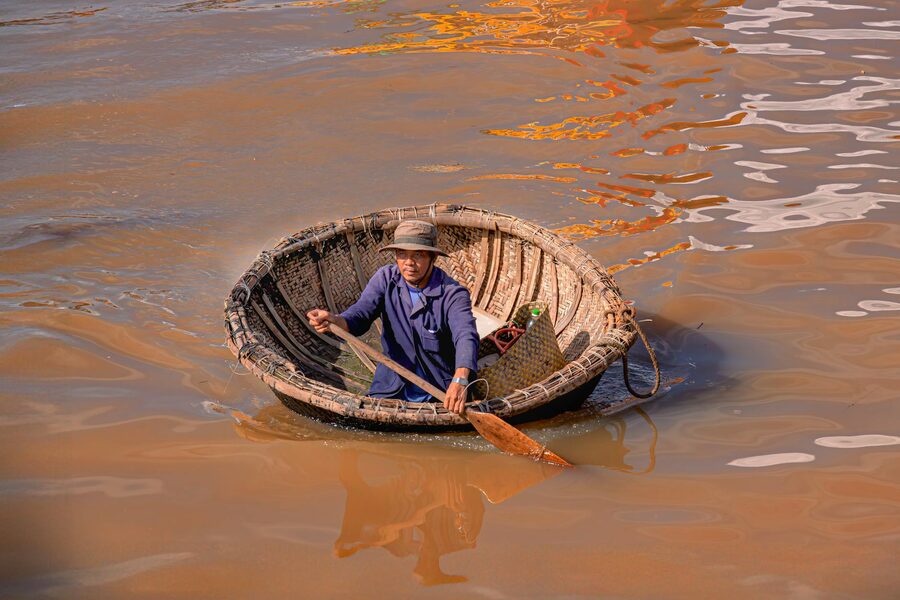 Man rowing a traditional basket boat on a river in Vietnam
