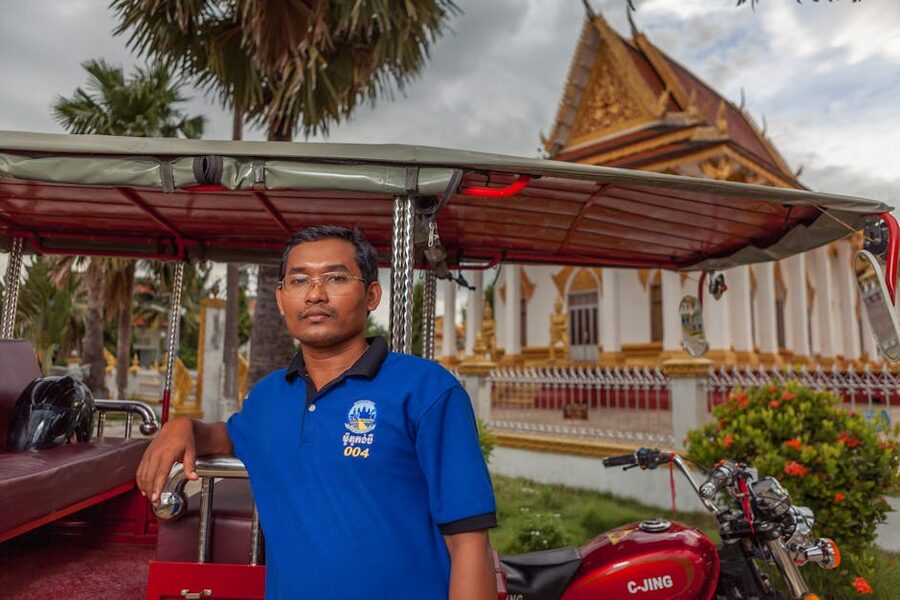 Tuk tuk driver posing in Battambang with temple background