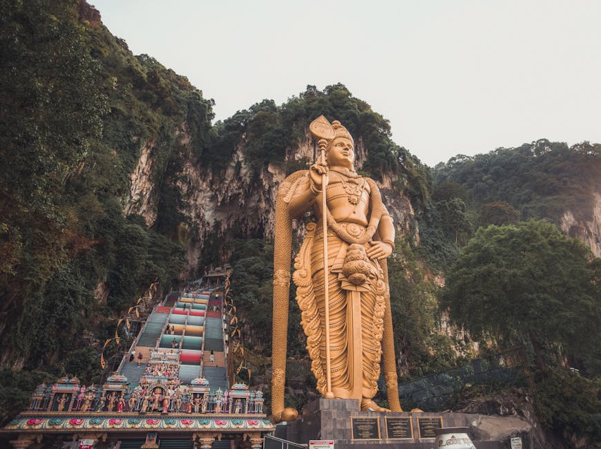 Golden Murugan statue with the limestone Batu Caves hill behind