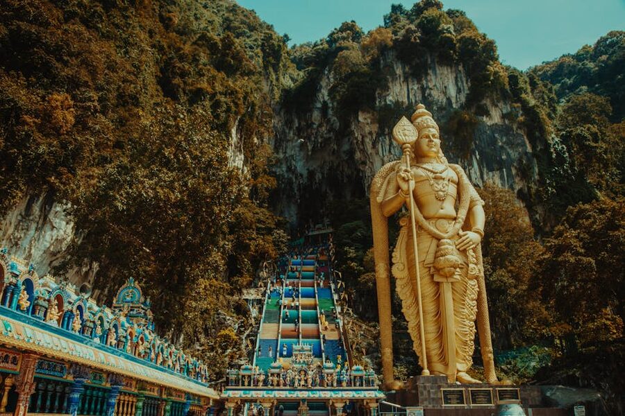 The Lord Murugan statue at Batu Caves surrounded by green tropical vegetation