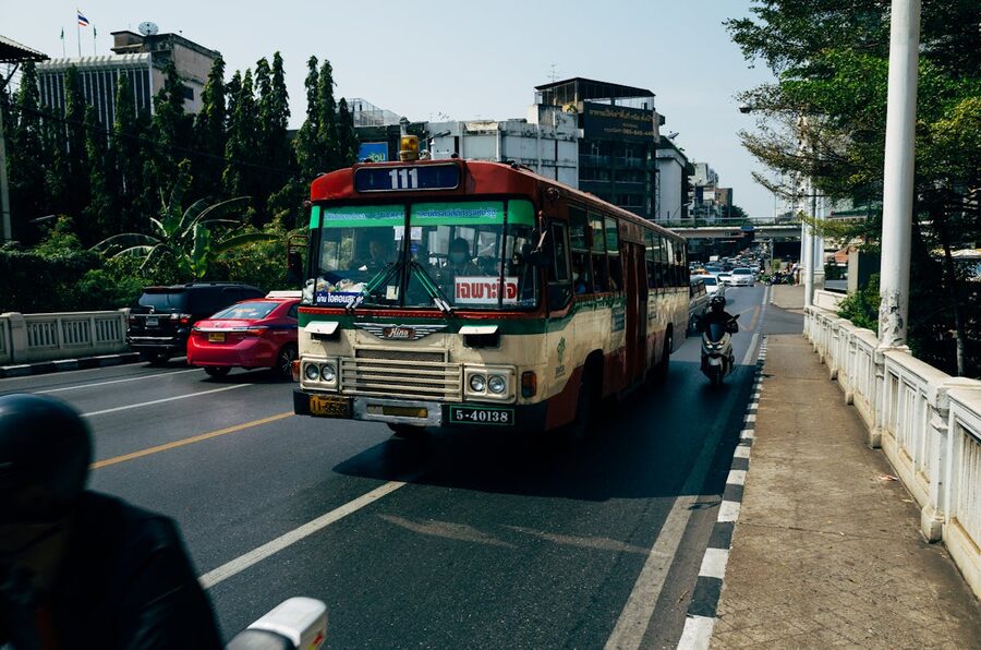 Public bus navigating a busy Bangkok street with traffic