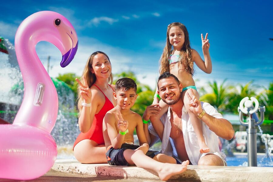 Family enjoying a sunny day by the pool with a pink flamingo float