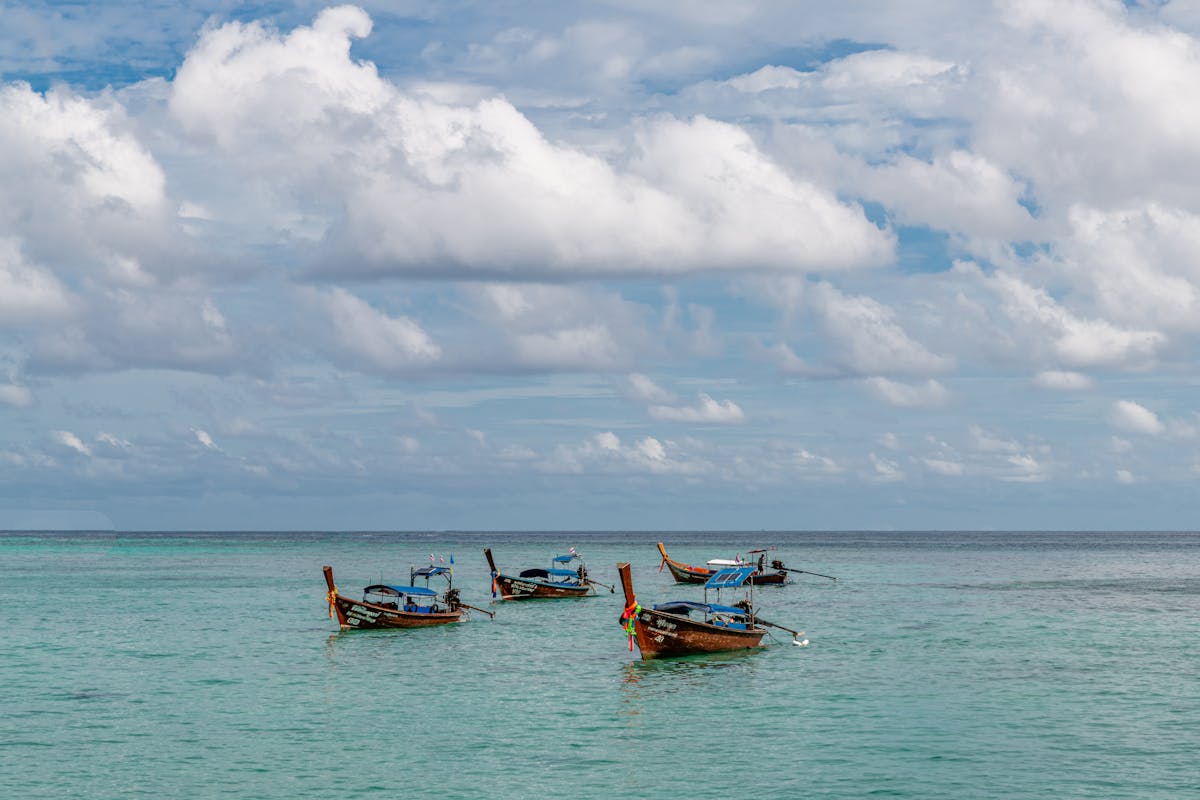 Traditional longtail boats floating on clear turquoise waters in Phuket Thailand