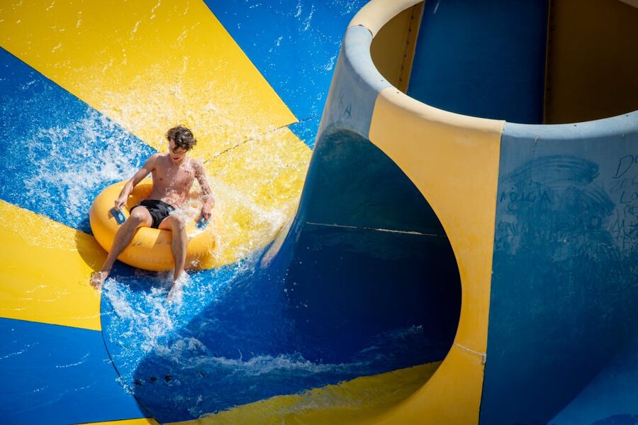 Person enjoying a thrilling ride on a colorful waterslide at a water park