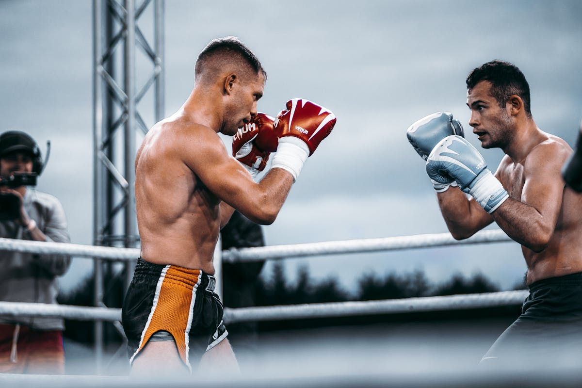 Two male fighters compete in an outdoor boxing match