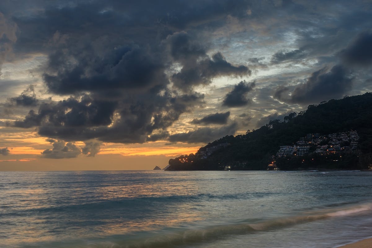Sunset over Patong Beach Phuket with dramatic clouds and calm waves