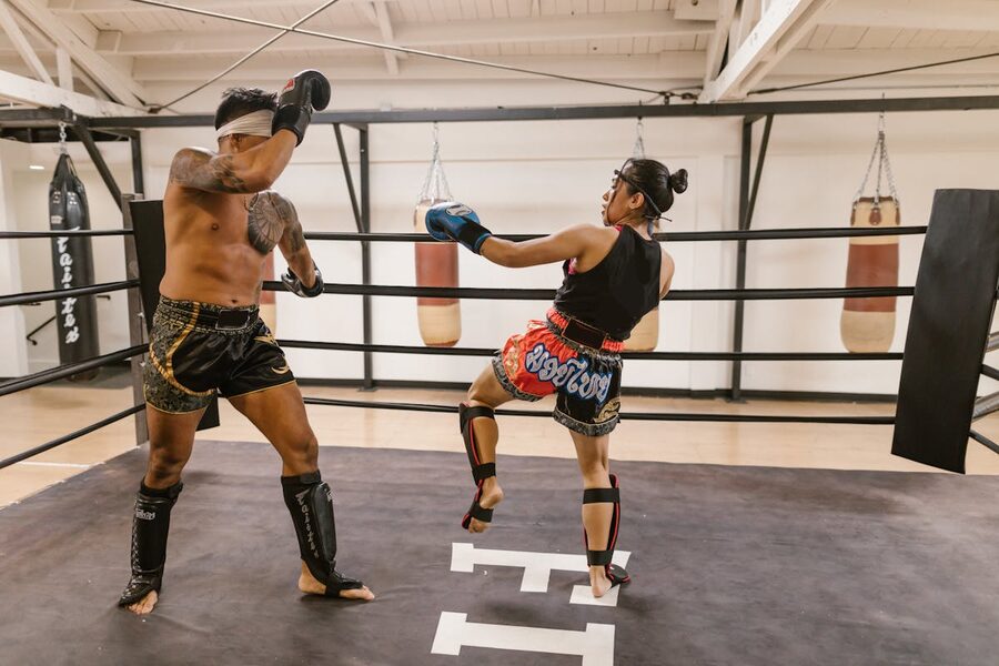 Two athletes in a Muay Thai sparring session inside a gym boxing ring