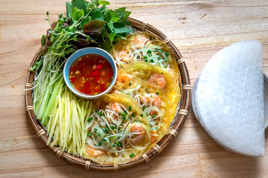 Top view of Vietnamese banh xeo pancake with fresh herbs and chili sauce