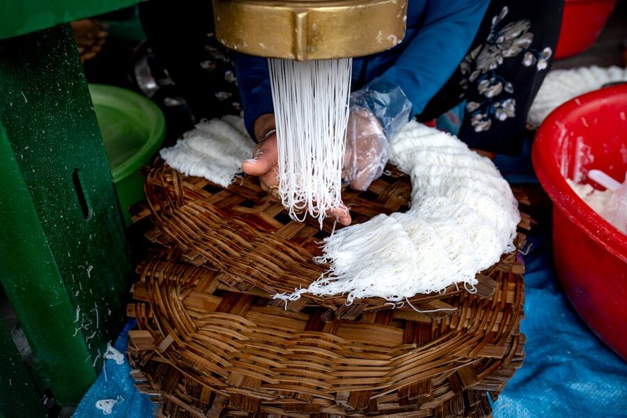 Close-up of traditional rice noodle making on woven trays in Vietnam