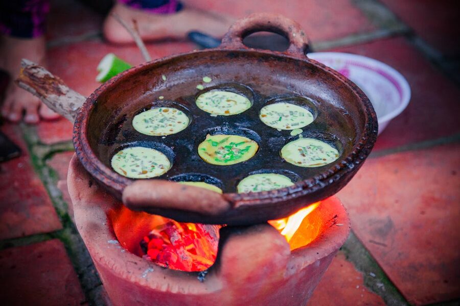 Vietnamese street food sizzling in a clay pan over a charcoal stove