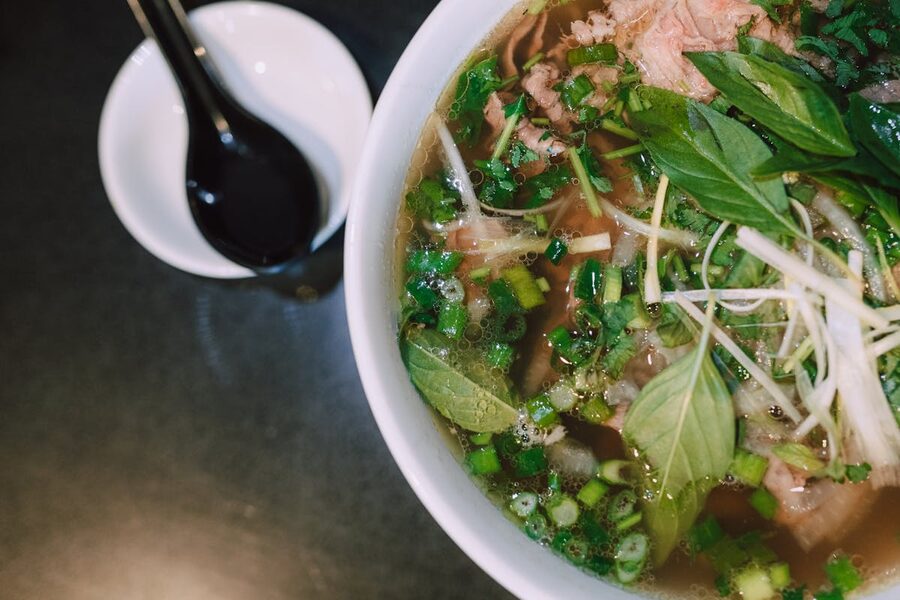 Bowl of traditional Vietnamese pho soup with fresh herbs and toppings