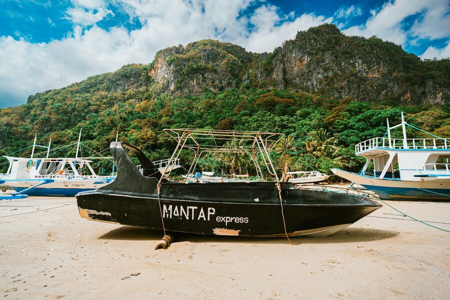 A beached traditional boat with a lush mountain backdrop
