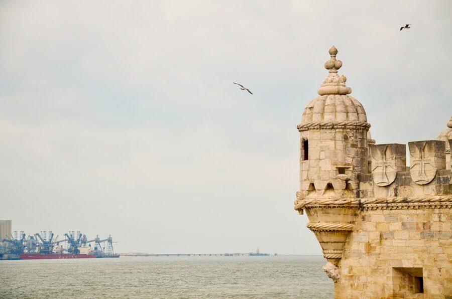 Belém Tower by the Tagus River with birds in flight