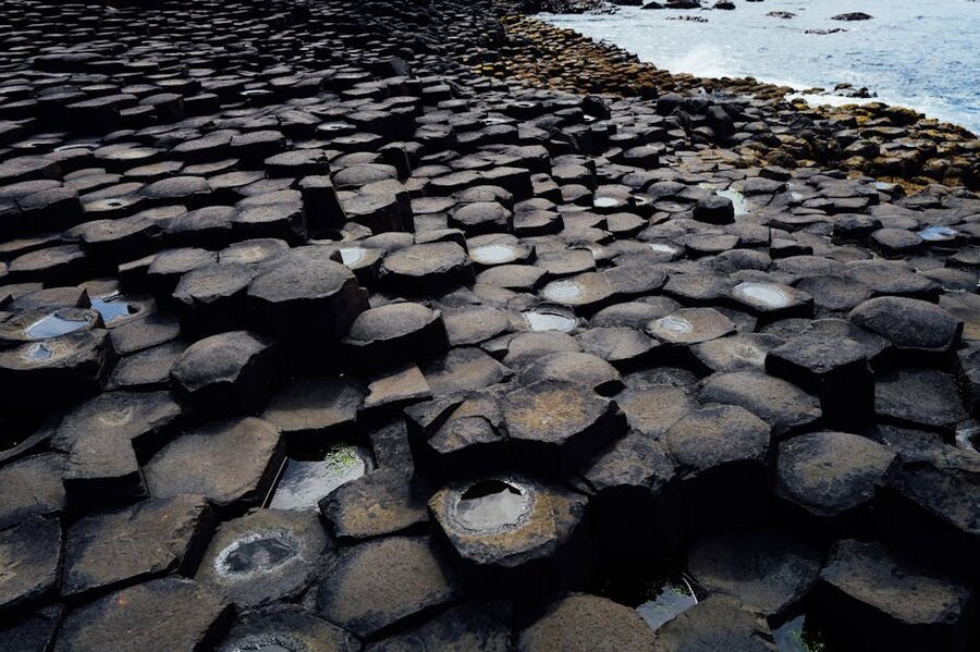 Interlocking hexagonal basalt columns of the Giants Causeway by the rugged coastline