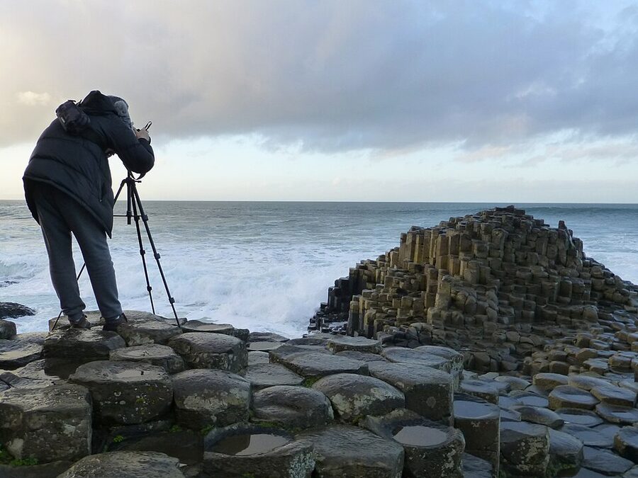 A photographer with tripod working on the Giants Causeway hexagonal columns
