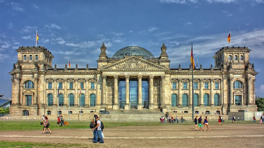 Reichstag front entrance with German flags and visitors waiting