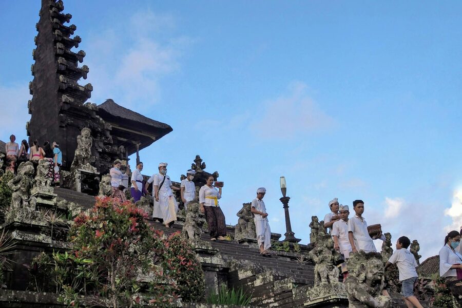 Worshippers in traditional white and yellow attire at Besakih Temple during a ceremony