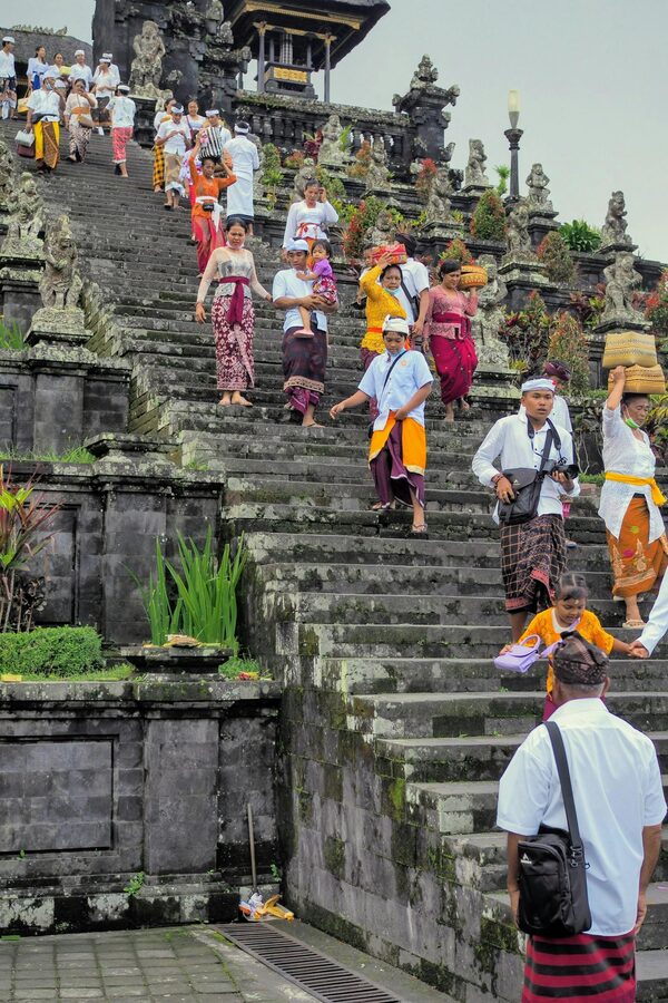People in traditional Balinese ceremonial white attire descending the steps of Besakih Temple