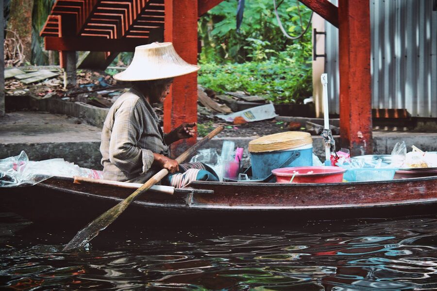 Local Thai vendor paddling a boat on the canal selling goods