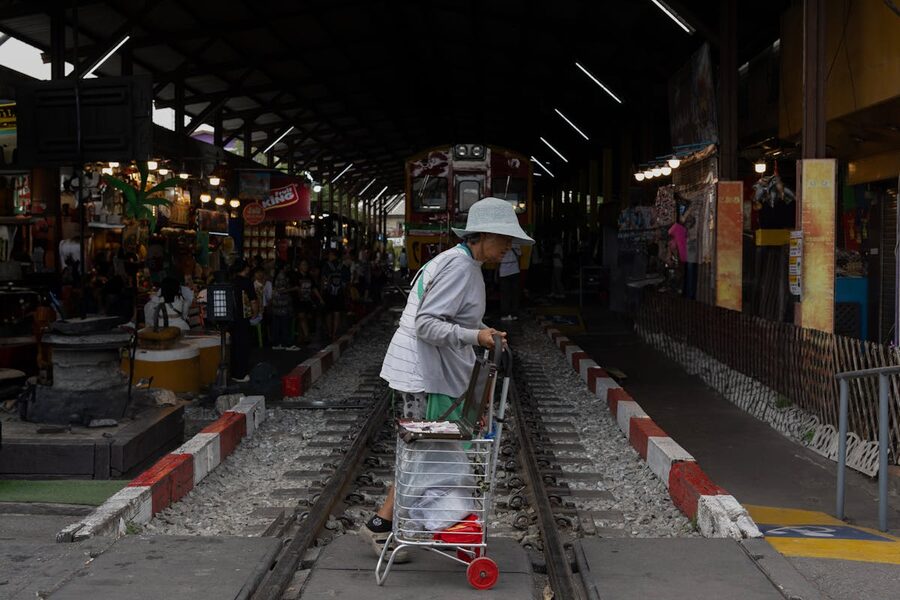 Elderly woman crossing train tracks at Maeklong Railway Market