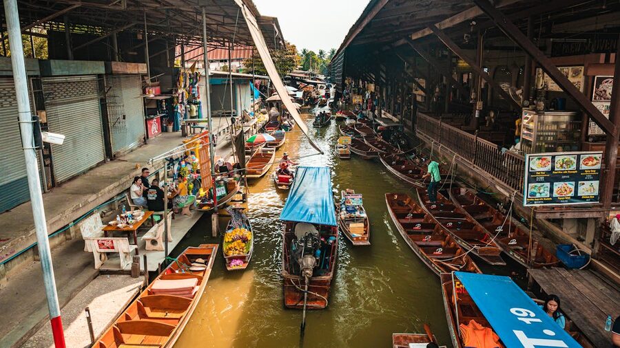 Colorful boats and vendors along a floating market canal in Thailand