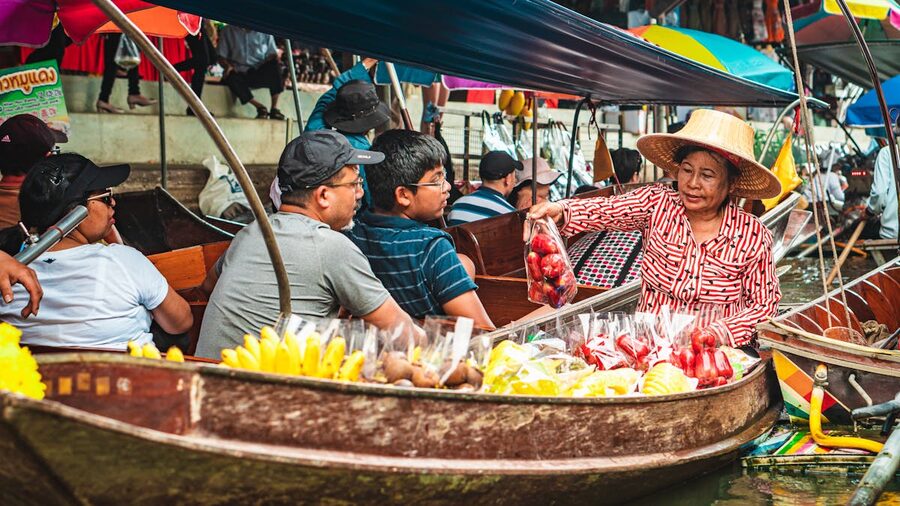 Tourists buying tropical fruits from vendors at Bangkok floating market